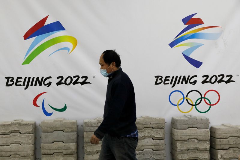 FILE PHOTO: Man walks past a board with logos of 2022 Winter Olympic Games, at a souvenir shop under renovation in Beijing