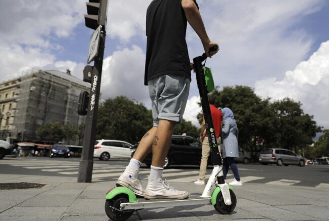 File - A man is seen riding an electric scooter. (AP Photo/Lewis Joly)