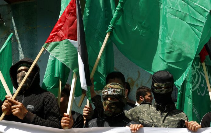 Masked Hamas militants wave green Islamic flags during a rally in solidarity with fellow Palestinians in Jerusalem and against Palestinian President Mahmoud Abbas decision to postpone Palestinian elections, in Jebaliya refugee camp, Gaza Strip, Friday, April 30, 2021. (AP Photo/Adel Hana)