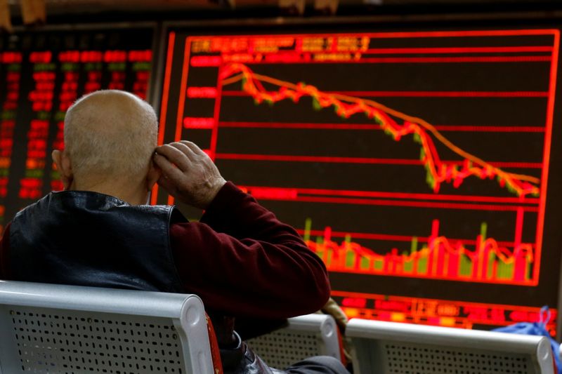 FILE PHOTO: An investor sits in front of a board showing stock information at a brokerage office