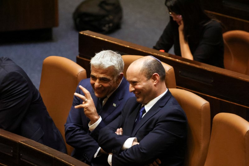 Prime Minister Naftali Bennett chats with Foreign Minister Yair Lapid, following the vote for the new coalition at the Knesset, Israel's parliament, in Jerusalem