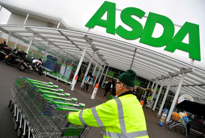 FILE PHOTO: FILE PHOTO: A worker pushes shopping trolleys at an Asda store in West London, Britain