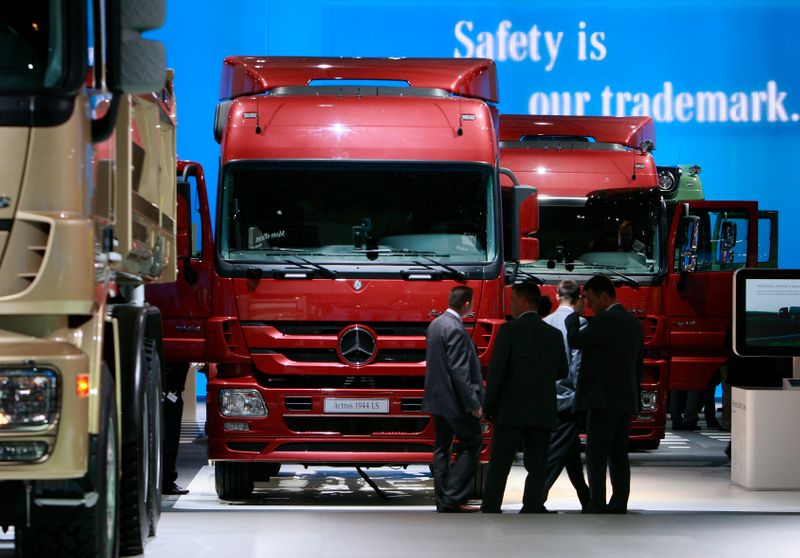 Visitors stend in front of a display of Daimler trucks during a preview day at the IAA commercial vehicles trade fair in Hanover