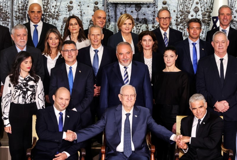 Israel's President Reuven Rivlin sits next to Prime Minister Naftali Bennett and Foreign Minister Yair Lapid as they pose for a group photo with ministers of the new Israeli government,