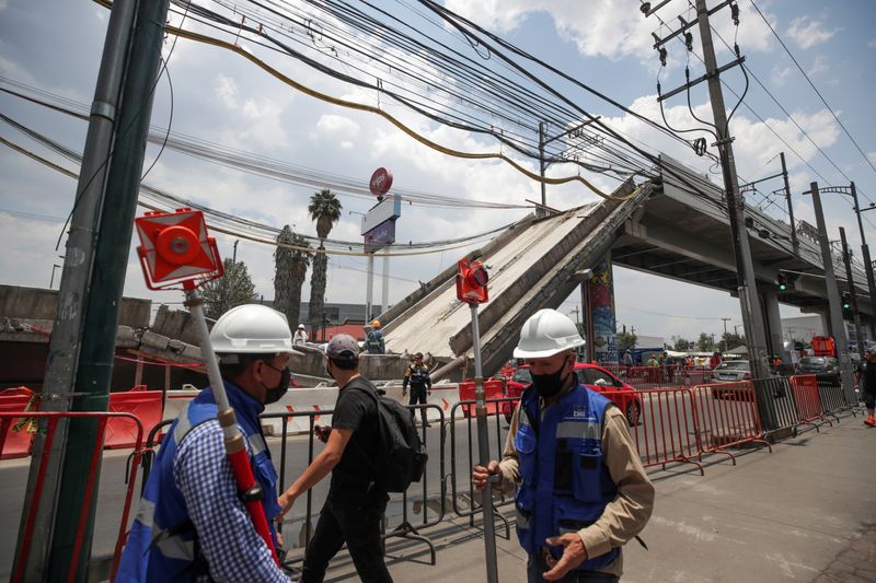 FILE PHOTO: Employees work as part of the investigations in front of the site where an overpass for a metro partially collapsed with train cars on it, in Mexico City