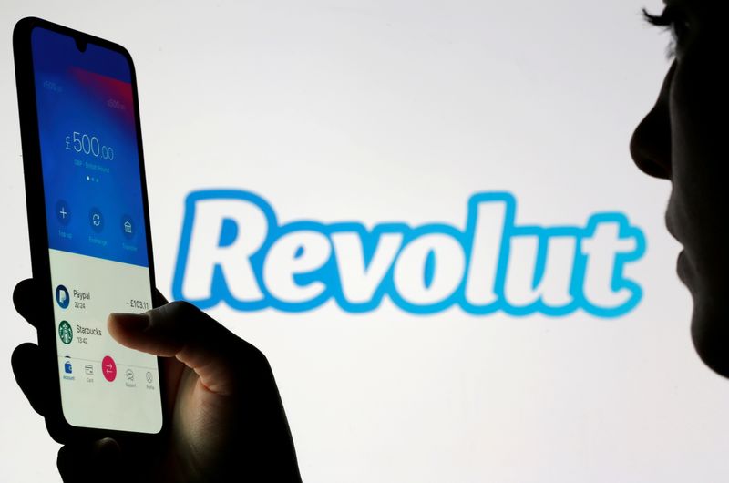 FILE PHOTO: Woman holds smartphone with Revolut app in front of displayed Revolut logo in this illustration