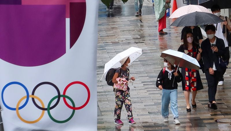 People walk on a street next to an advertisement for Tokyo 2020 Olympic and Paralympic Games