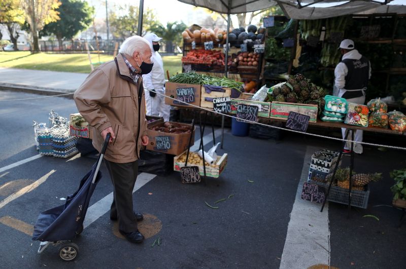 FILE PHOTO: A customer walks outside a shop at a greengrocery store in a street market, in Buenos Aires