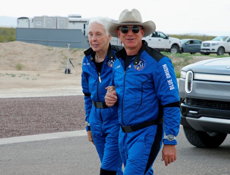Billionaire American businessman Jeff Bezos walks with crewmate Wally Funk at the landing pad after they flew on Blue Origin's inaugural flight