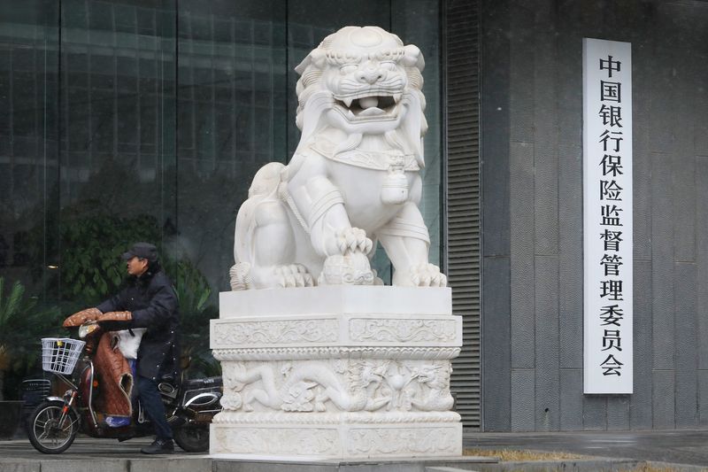 FILE PHOTO: A man rides an electric bike past the CBIRC building in Beijing