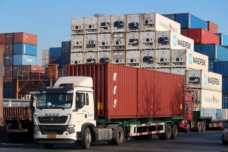 Worker drives a truck carrying a container at a logistics center near Tianjin port