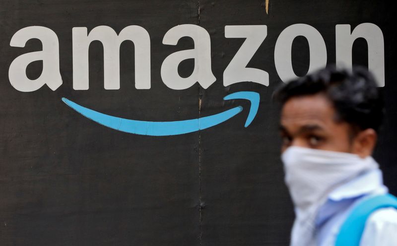 FILE PHOTO: A man walks past an Amazon logo outside the company's collection point in Mumbai