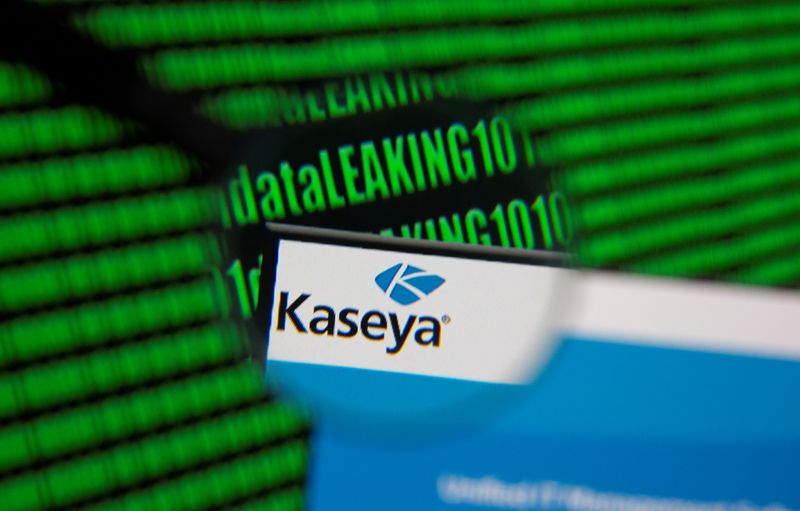 Kaseya's webpage is seen through magnifying glass in front of displayed binary code