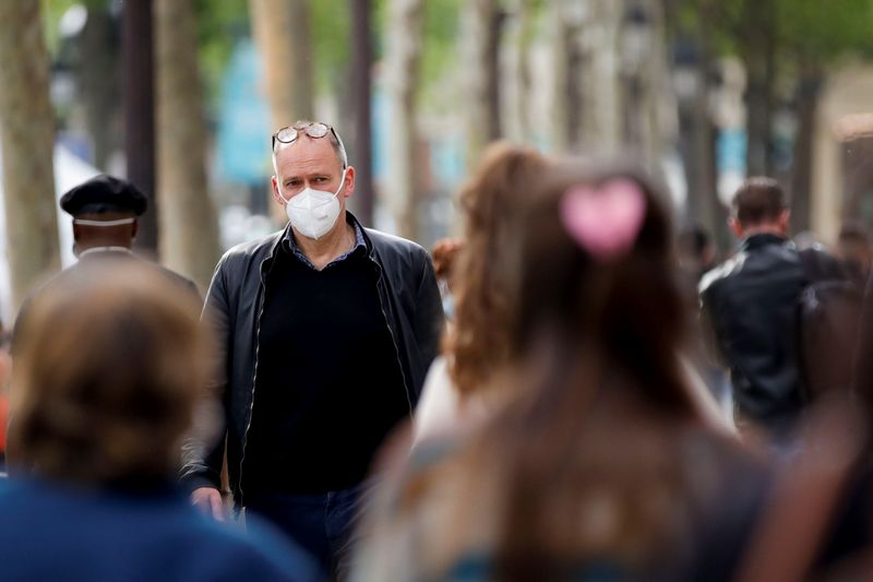 People wearing protective face masks walk in Paris