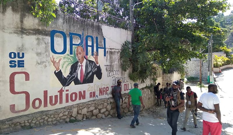 People walk past a wall with a mural depicting Haiti's President Jovenel Moise, after he was shot dead by unidentified attackers in his private residence, in Port-au-Prince