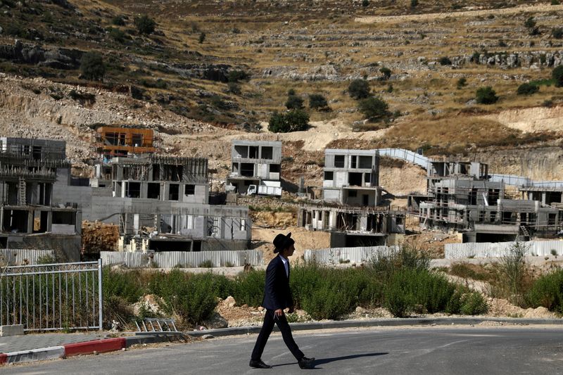 FILE PHOTO: A Jewish settler walks past Israeli settlement construction sites around Givat Zeev and Ramat Givat Zeev in the Israeli-occupied West Bank