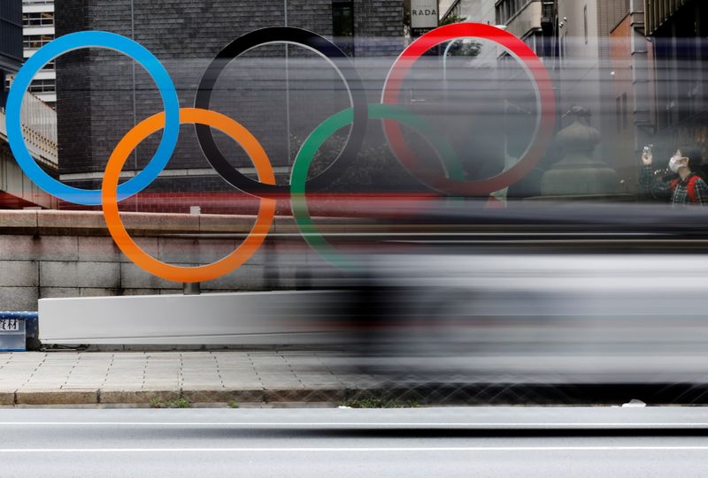 FILE PHOTO: A woman wearing a protective mask takes a photo of Olympic Ring promoting Tokyo 2020 Olympic Games in Tokyo, Japan, July 12, 2021.