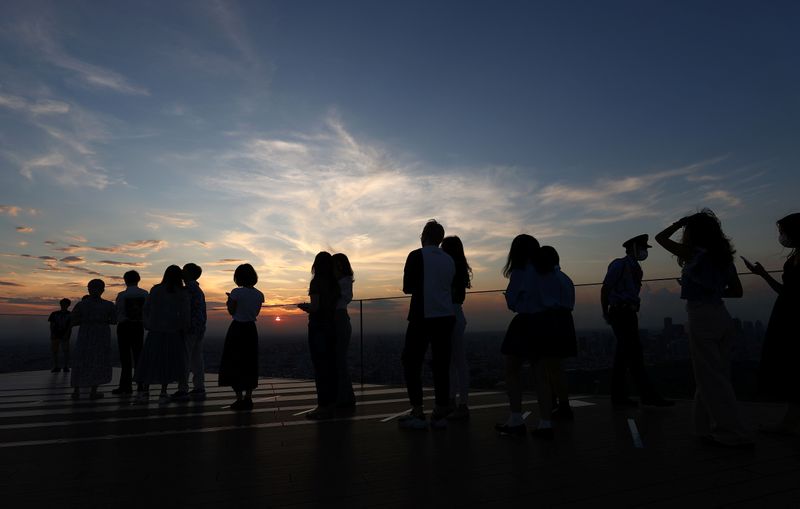 People queue up to get their picture taken in front of the sunset on top of Shibuya Sky observation deck, in Tokyo