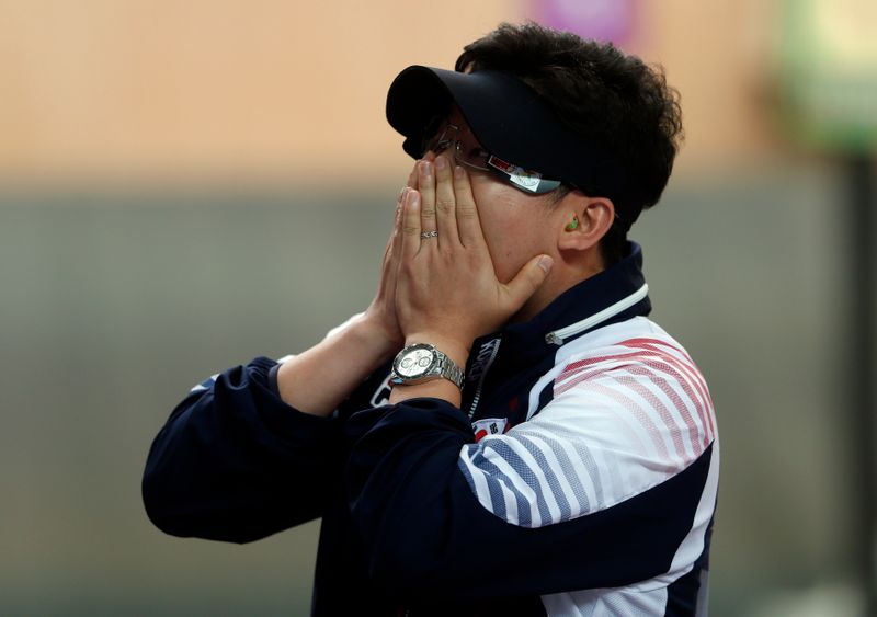 South Korea's Jin Jong-oh covers his face after winning the men's 10m air pistol final at the London 2012 Olympic Games in the Royal Artillery Barracks at Woolwich in London