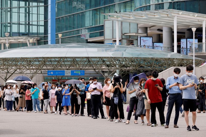 FILE PHOTO: People wait in line for a coronavirus disease (COVID-19) test at a testing site which is temporarily set up at a railway station in Seoul