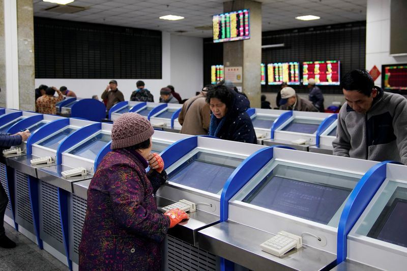 Investors look at computer screens showing stock information at a brokerage house in Shanghai