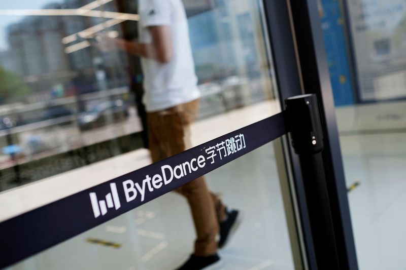 FILE PHOTO: FILE PHOTO: Man walks by a logo of Bytedance, which owns short video app TikTok, at its office in Beijing