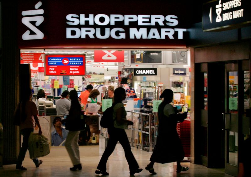 FILE PHOTO: People walk past a Shoppers Drug Mart store in Toronto
