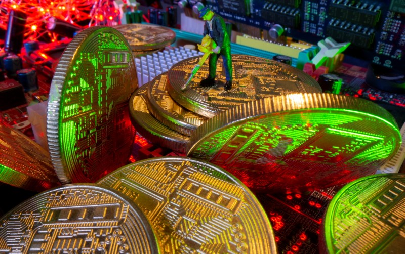 FILE PHOTO: A small toy figure and representations of virtual currency stand on a motherboard in this picture illustration