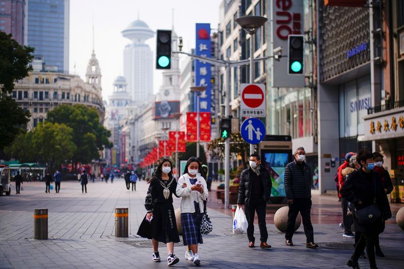 FILE PHOTO: FILE PHOTO: People wearing face masks walk at a main shopping area in Shanghai