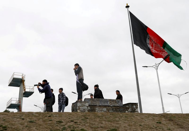 FILE PHOTO: Youths take pictures next to Afghan flag in Kabul
