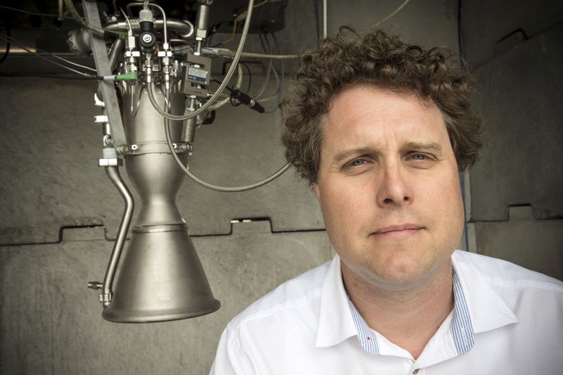 Rocket Lab CEO Peter Beck poses alongside a Rutherford rocket engine in Auckland