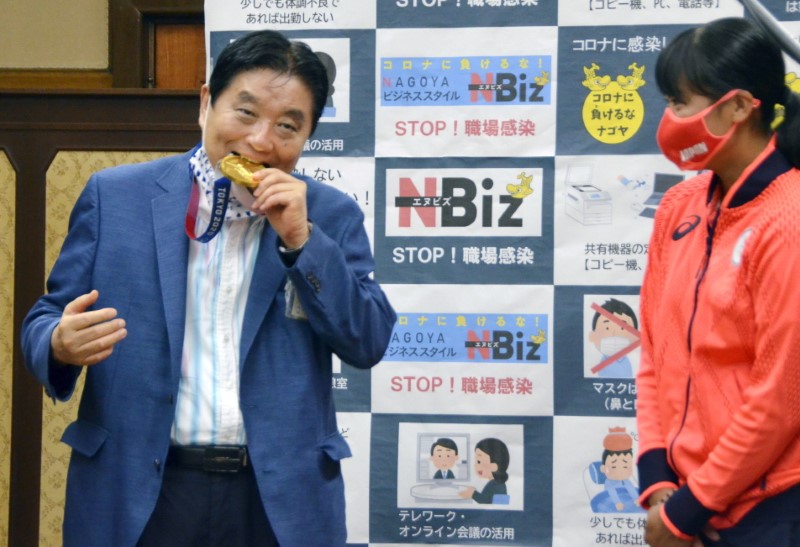 FILE PHOTO: Nagoya city Mayor Takashi Kawamura bites the Tokyo 2020 Olympic Games gold medal of the softball athlete Miu Goto in Nagoya, Japan