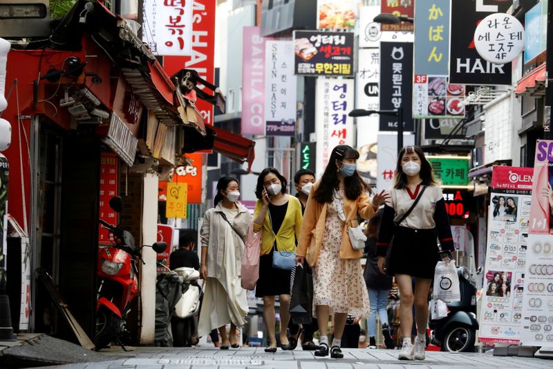 FILE PHOTO: People wearing masks walk at Myeongdong shopping district amid social distancing measures to avoid the spread of the coronavirus disease (COVID-19), in Seoul