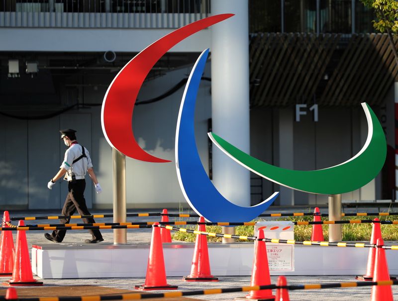 A security guard wearing a protective mask walks past the symbol of the Paralympic Games, in Tokyo