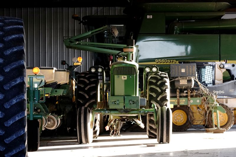 FILE PHOTO: A John Deere tractor, a combine, and other heavy machinery sit inside a barn on a corn and soybean farm in Woodburn, Indiana