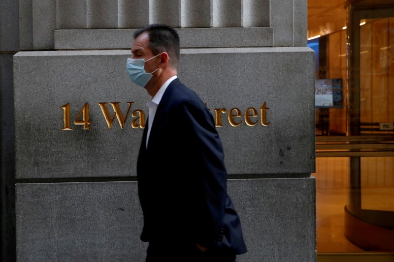 FILE PHOTO: A man wearing a protective face mask walks by 14 Wall Street in the financial district of New York