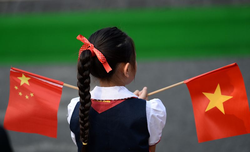 A Vietnamese pupil holds Vietnamese and Chinese flags before the welcoming ceremony at the Presidential Palace in Hanoi