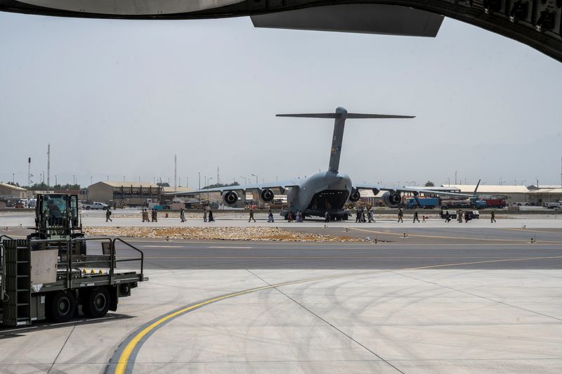 U.S. Department of Defense service members provide security while escorting evacuees at Hamid Karzai International Airport