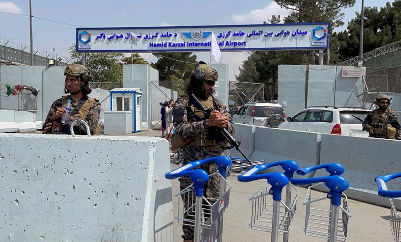 FILE PHOTO: Taliban forces stand guard at the entrance gate of Hamid Karzai International Airport a day after U.S troops withdrawal in Kabul