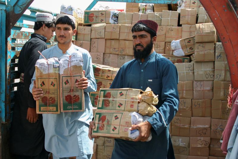 FILE PHOTO: Labourers unload boxes of pomegranates from Afghanistan, from a truck at the 'Friendship Gate' crossing point, in the Pakistan-Afghanistan border town of Chaman