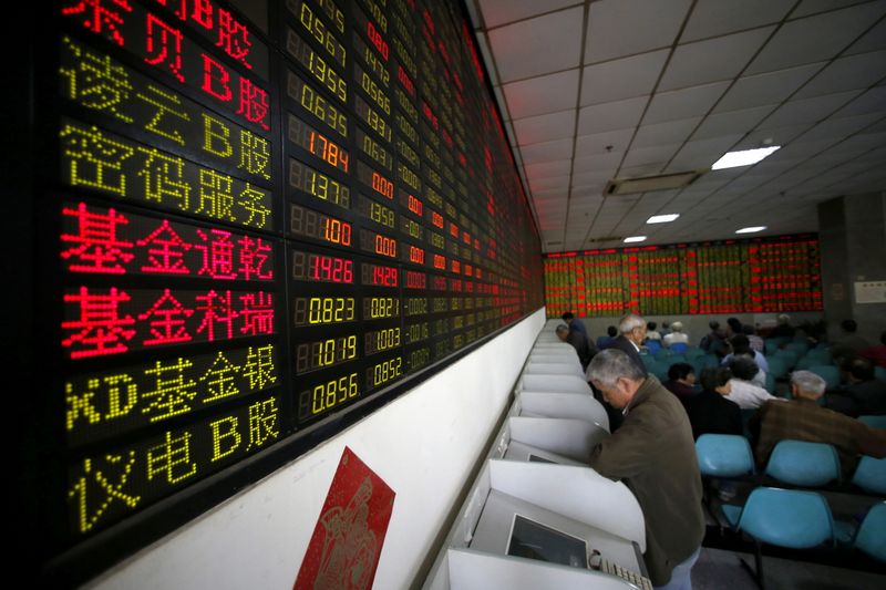 FILE PHOTO: Investors look at computer screens showing stock information at a brokerage house in Shanghai