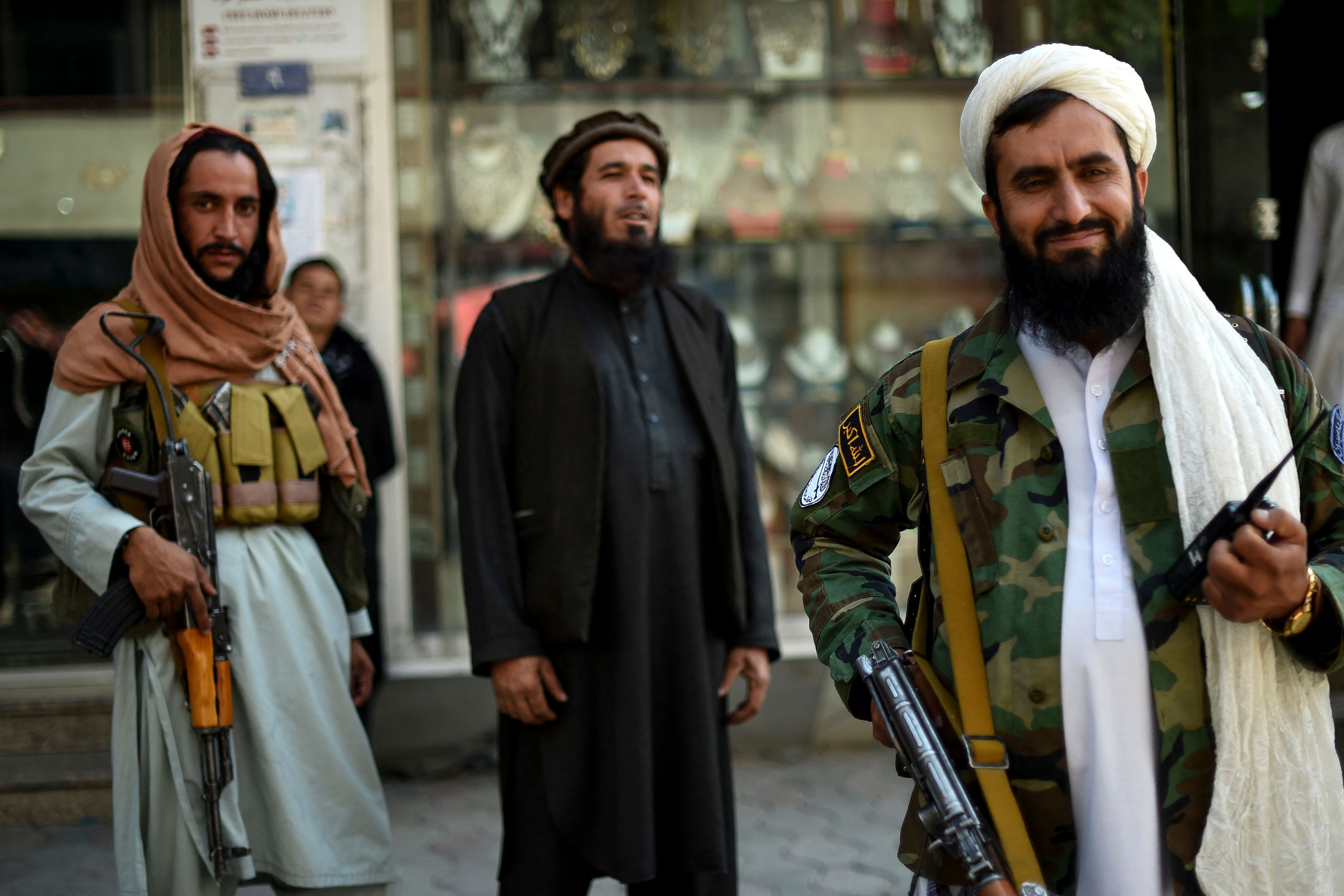 Taliban fighters stand guard on the backdrop of shops selling antiques and decorative merchandise at Chicken Street in Kabul on September 26, 2021.(Photo by WAKIL KOHSAR/AFP via Getty Images)