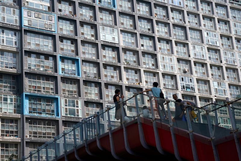 FILE PHOTO: People wearing face masks are seen on an overpass in front of a residential building in Beijing