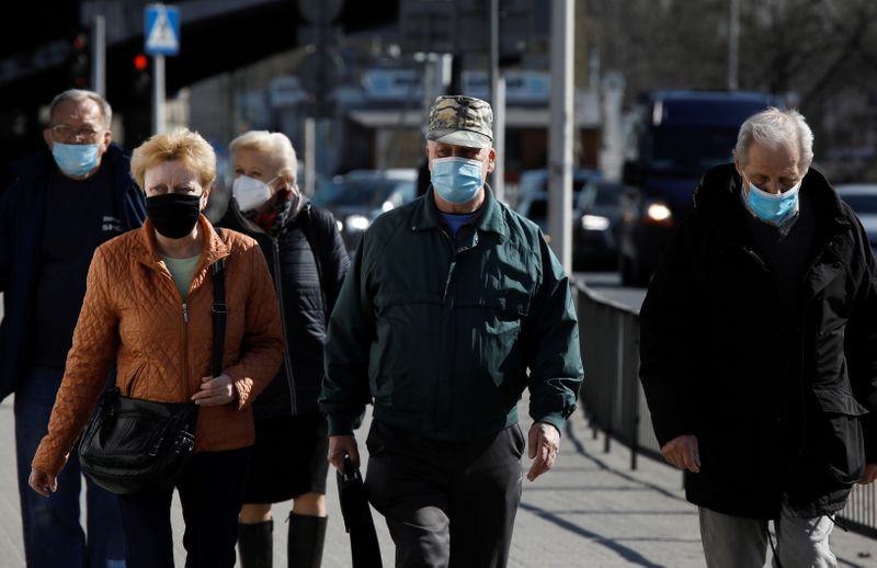 FILE PHOTO: People wearing protective masks walk in Warsaw