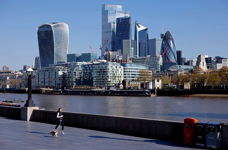 FILE PHOTO: A woman exercises with a dog near the City of London financial district, in London