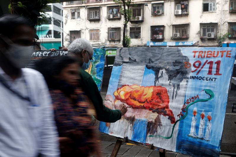 People walk past a 9/11 tribute on the 20th year anniversary outside an art school in Mumbai