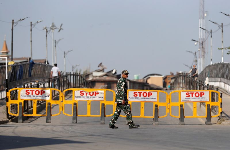 An Indian security force personnel member walks past barricades during restrictions imposed by authorities following the death of Syed Ali Shah Geelani, in Srinagar