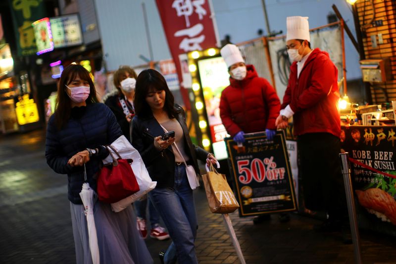 People, wearing protective masks following an outbreak of the coronavirus disease (COVID-19), walk on an almost empty street in the Dotonbori entertainment district of Osaka