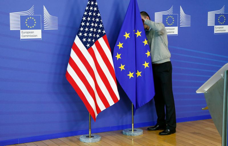 FILE PHOTO: A worker adjusts EU and U.S. flags at the start of the 2nd round of EU-US trade negociations at the EU Commission headquarters in Brussels