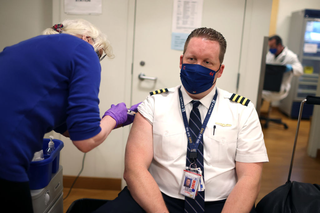 CHICAGO, ILLINOIS - MARCH 09: United Airlines pilot Steve Lindland receives a COVID-19 vaccine from RN Sandra Manella at United's onsite clinic at O'Hare International Airport on March 09, 2021 in Chicago, Illinois. United has been vaccinating about 250 of their O'Hare employees at the clinic each day for the past several days. (Photo by Scott Olson/Getty Images)